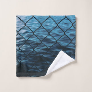 Body of water in front of chain link fence wash cloth