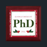Border Red Green Holly Name Year PhD Graduation Gift Box<br><div class="desc">A square Phd graduation keepsake box with a Christmas feel. The top has a decorative border and a holly berry and leaf accents. It has a red, green, and white colour scheme and shows the degree, name, and year. Simply customise this box, add it to your cart, and give it...</div>