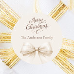 Bow cream beige mocha Christmas Classic Round Sticker<br><div class="desc">A cream,  beige background,   and bow.  Merry Christmas is written with an elegant hand-lettered style script.  Personalise and add your family name.  Mocha,  muted brown coloured text.</div>
