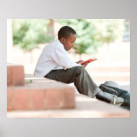 Boy reading on steps outside school,