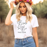 Bride to Be Script Calligraphy Name T-Shirt<br><div class="desc">Celebrate the bride-to-be with this gorgeous script calligraphy tee featuring "Bride to Be" in flowing hand-lettered typography and a customisable first name. A beautiful monogram keepsake for engagement parties,  bridal showers,  and bachelorette weekends. Edit the name to personalise for the guest of honour.</div>