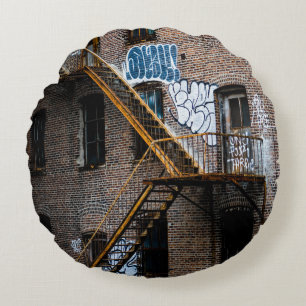 BROWN BRICK BUILDING WITH YELLOW METAL LADDER ROUND CUSHION