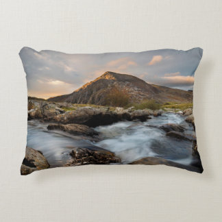 BROWN MOUNTAIN NEAR BODY OF WATER UNDER CLOUDY SKY DECORATIVE CUSHION