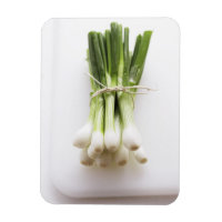 Bunch of spring onions on white chopping board