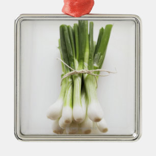 Bunch of spring onions on white chopping board metal tree decoration
