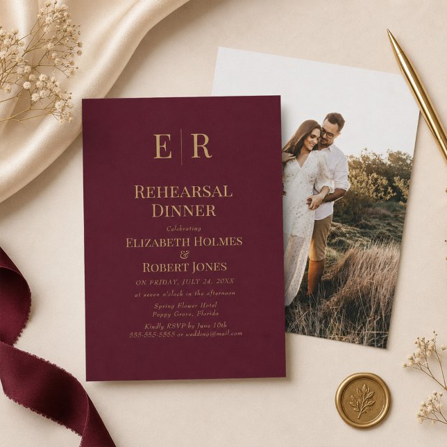 Burgundy Gold Monogram Rehearsal Dinner Invitation (Burgundy Gold Monogram Rehearsal Dinner Invitation on a table with elegant wedding decor)