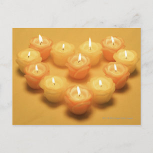 Burning candles arranged in a heart shape postcard