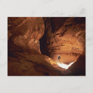 Canyoneer illuminated in the depths of a narrow postcard