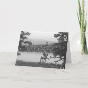 Cattle by a pond with two cowboys. card