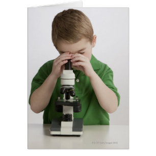 Caucasian boy peering into microscope