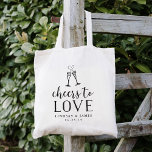Cheers to Love Wedding Favour Tote Bag<br><div class="desc">Festive and chic wedding favour or wedding welcome tote bags feature "cheers to love" in black vintage style block and script typography with two champagne flutes joined by an effervescent heart. Personalise with your names and wedding date beneath.</div>