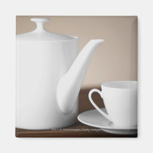Close-up of a cup and a saucer with a tea kettle magnet