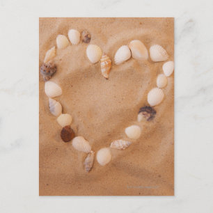 Close up of heart shape made of shells on sand postcard