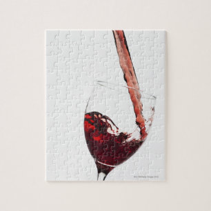 Close up of red wine being poured into glass on jigsaw puzzle