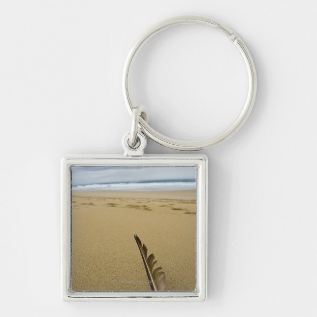 Close-up view of bird feather in beach sand, key ring (Front)