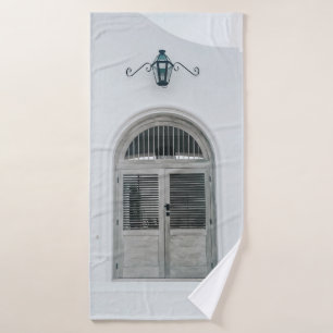 CLOSED GREY WOODEN DOOR BELOW BLACK LIGHT SCONCE BATH TOWEL