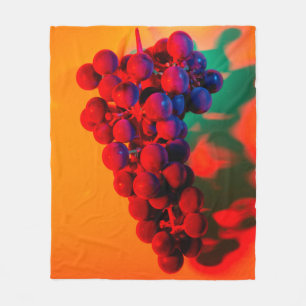 Cluster of blue grape in orange neon light. Food b Fleece Blanket