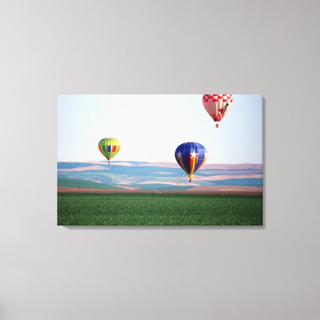 Colourful hot air balloons float over wheat canvas print (Front)