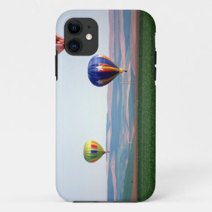 Colourful hot air balloons float over wheat iPhone 11 case