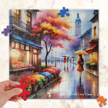Colourful Rainy Day in the City Watercolor Puzzle<br><div class="desc">Puzzle featuring a watercolor painting of a girl with an umbrella walking past a flower shop on a rainy day in town.</div>