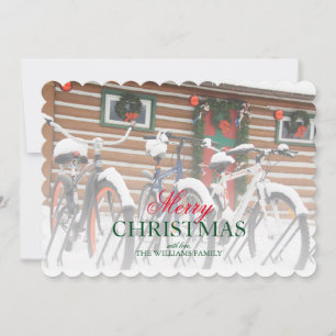 Couple of snow covered bikes near wreathed lodge holiday card