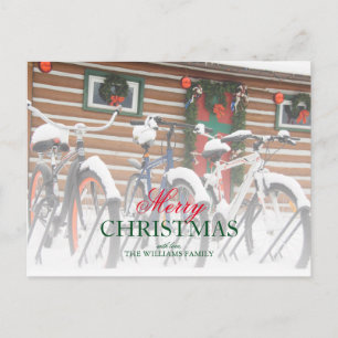 Couple of snow covered bikes near wreathed lodge holiday postcard