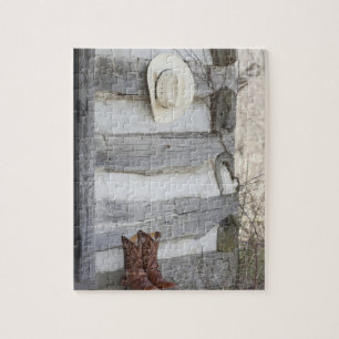 Cowboy boots and hat outside of log cabin jigsaw puzzle