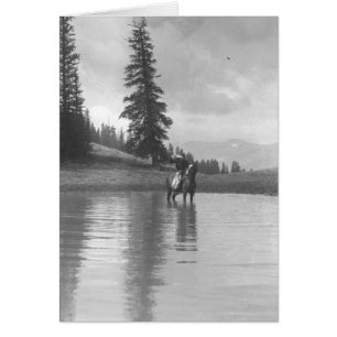 Cowboy on a horse standing in a pond drinking from