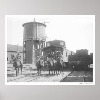 Cowboys on horses posing in front of a train poster