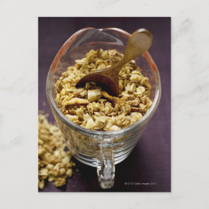 Crunchy muesli with wooden spoon in a measuring postcard