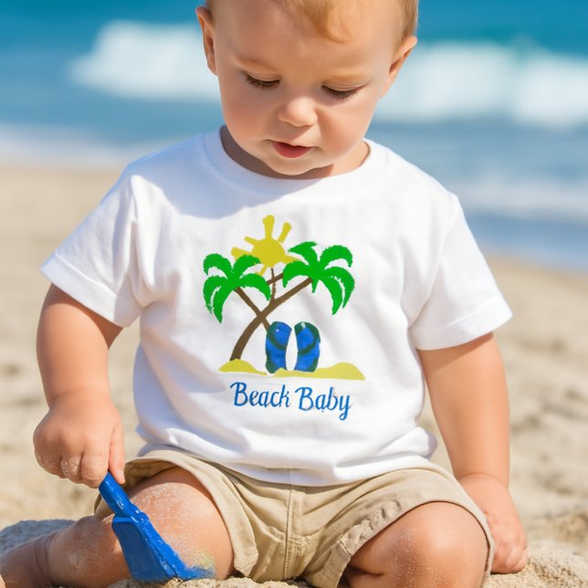 Cute Beach Baby  Baby T-Shirt (a toddler playing in the sand with a small blue shovel, wearing a white crewneck short-sleeve tee-)