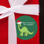 Cute Christmas Dinosaur in Santa Hat Custom Kids Classic Round Sticker<br><div class="desc">Awesome green dinosaur smiling and looking very cute in a holiday red Santa hat. Kids will love this cool green holiday party favour label. Customise these Christmas gift sticker with your own text in white.</div>