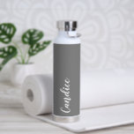 Dark Grey Personalised Wedding Bridesmaid Water Bottle<br><div class="desc">Gift your wedding bridesmaid or maid of honour with this trendy, vacuum Insulated water bottle that features her name in white, stylised script on a dark grey colour background designed to match your wedding colour scheme. Personalise bottle by editing and replacing name with your own as desired. Select your water...</div>
