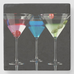 Different cocktails in martini glasses on black stone coaster