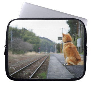 Dog sitting on train station laptop sleeve