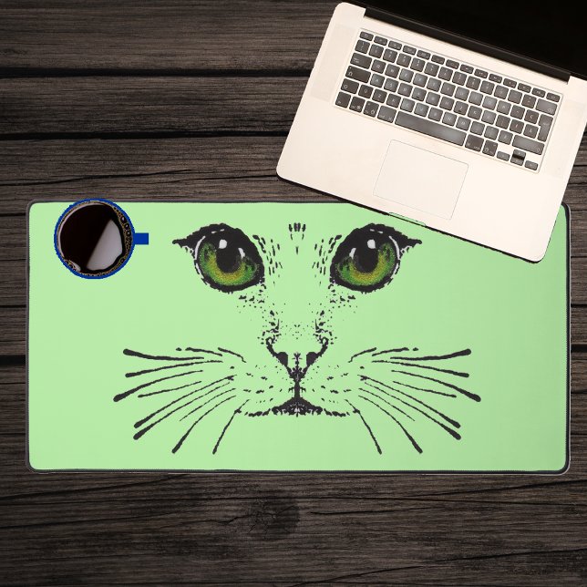 Drawing Black Cat Face Intense Green Eyes Whiskers Desk Mat (Black illustration of the face of a cat with green eyes long whiskers on light green desk mat.)