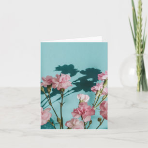 Dreamy pink carnation flowers on blue background card
