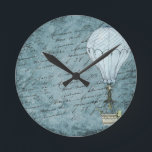 Dusk Blue Hot Air Balloon Steampunk Handwriting Round Clock<br><div class="desc">Matches other Steampunk hot air balloon design items such as cards and wrapping paper. Great for aviators and other air travel fans. This design features a Victorian Steampunk Hot Air Balloon gently flying in front of a scrapbook background page filled with handwriting washed with shades of soft, dusk blue. This...</div>