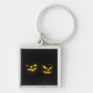 Eerie yellow glow pumpkin faces on black key ring