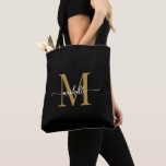 Elegant Black Gold Girly Personalised Monogrammed  Tote Bag<br><div class="desc">Girly Modern Simple Elegant Black and Gold Monogram Initial Name Signature Script Custom Personalised Tote Bag. This design featuring your first name in a pretty hand lettered style swash tail font typography (or calligraphy) with monogram initial in gold and white on black. Great feminine gift for birthday, wedding, Christmas, sweet...</div>