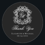 Elegant Black Monogram Wedding Crest Thank You Classic Round Sticker<br><div class="desc">These elegant classic black and white wedding monogram thank you stickers are perfect for favors, place cards, and more. They feature an ornate vintage crest with intertwined fancy script calligraphy monogram, and script Thank You. Find matching products in the collection, or message me through Zazzle Chat for more products and...</div>