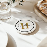 Elegant Brass Black Round Monogram Script Coaster<br><div class="desc">An elegant sandstone coaster featuring a warm brass gold serif initial and custom family name in script, framed by a black circle on a crisp white background. The luxurious brass and black combination delivers a sophisticated, elevated accent for any tabletop. A beautiful personalised gift for weddings, housewarmings, or anniversaries. All...</div>