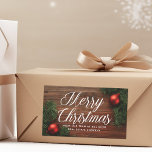 Elegant Company Merry Christmas Modern Custom Gift Rectangular Sticker<br><div class="desc">This classy company Christmas gift sticker features elegant white cursive typography over a beautiful holiday photograph. The photo features red ornaments and green mistletoe bordering a wood floor. This upscale corporate Christmas present label features your business name on the front and custom company message inside.</div>