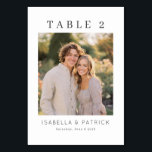 Elegant Wedding Table Number Card<br><div class="desc">This is a minimalist style image featuring a charming couple, Isabella and Patrick, on their wedding day. The photograph captures them in a warm embrace amidst lush greenery, bathed in the soft golden light of late afternoon. Their joyful expressions and casual elegance exude love and happiness. The card includes "TABLE...</div>