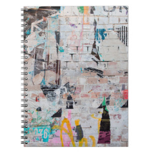 Exposed weathered brick wall with torn street post notebook