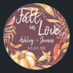 Fall in Love Burgundy Wedding Monogram Classic Round Sticker<br><div class="desc">"Fall in Love" rustic themed wedding favour stickers feature orange and golden autumn foliage, a fall watercolor pumpkin and customisable monogram of the bride and groom's names and wedding date on a burgundy background. Exclusively designed for you by Happy Dolphin Studio. If you need any help or matching products, please...</div>