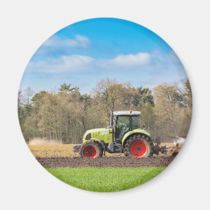 Farmer on tractor ploughing sandy soil in spring magnet