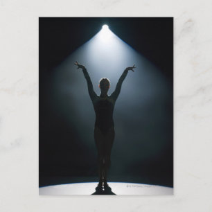 Female gymnast performing in spotlight, studio postcard