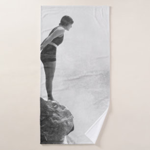 Female swimmer on rock above crashing surfvintage, bath towel