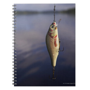 fishing lure in front of water spiral notebook